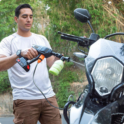 Hombre limpiando una motocicleta con la hidrolavadora portátil Inbogo